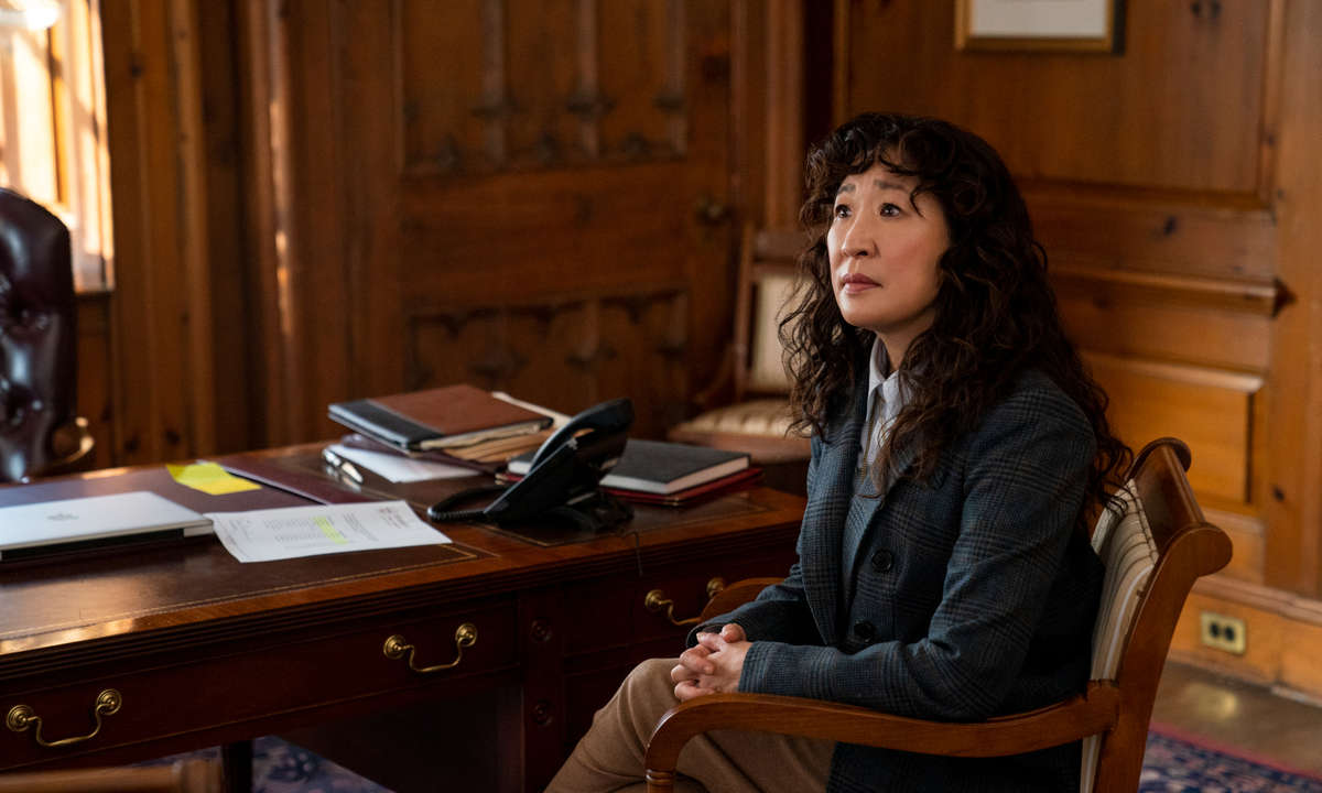 Sandra Oh sitzt auf einem Stuhl in einem vertäfelten Büro