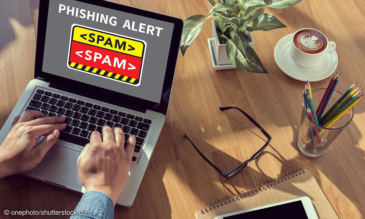 Mann tippt auf Laptopm, auf dem Bildschirm ist eine Phishing-Warnung zu sehen