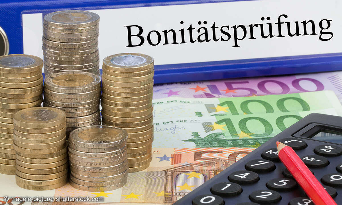 Auf einem Tisch liegt Geld und ein Schild auf dem Bonitätsprüfung steht